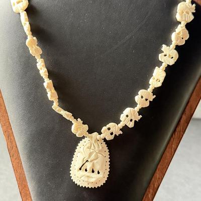 vintage hand-carved elephant necklace, likely made from bone, celluloid, or a similar material.
