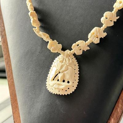 vintage hand-carved elephant necklace, likely made from bone, celluloid, or a similar material.
