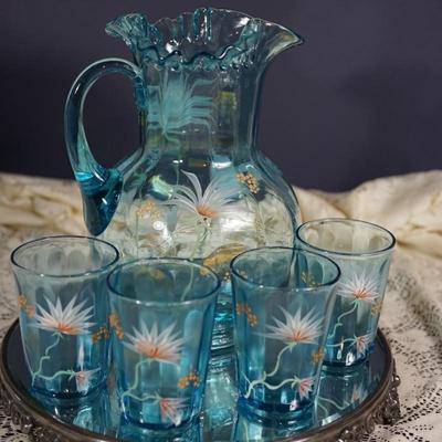 Sale Photo Thumbnail #187: This is a possible Northwood glass pitcher and four glasses from the 1890's-1900.
Beautiful blue glass with hand painted glasses and pitcher of exotic stylized flowers
brush gold colored leaves ( slight wear to a few of these) the enamelled dots accent. N