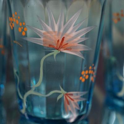Sale Photo Thumbnail #191: This is a possible Northwood glass pitcher and four glasses from the 1890's-1900.
Beautiful blue glass with hand painted glasses and pitcher of exotic stylized flowers
brush gold colored leaves ( slight wear to a few of these) the enamelled dots accent. N