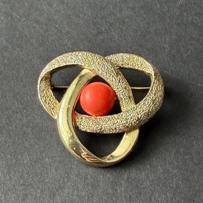 Sarah Coventry "Orbit" brooch in gold-tone metal with a faux coral cabochon center.