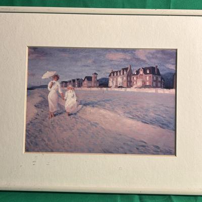 Sale Photo Thumbnail #12: A framed watercolor painting depicting two figures walking along a coastal shore near a group of buildings. The artwork uses soft tones to capture a serene seaside scene. The frame has a simple white border. No artist signature or other markings are visib