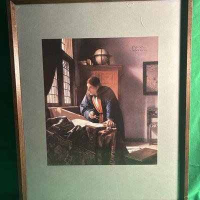 Sale Photo Thumbnail #22: Framed reproduction of Johannes Vermeer's painting titled 'The Geographer.' The artwork features a man in a study, examining a map with light streaming through a window. The piece is mounted on a green mat and encased in a wood frame. Condition appears to