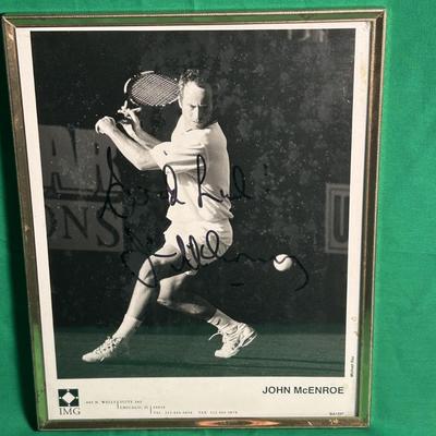 Sale Photo Thumbnail #47: Framed black-and-white photograph featuring tennis icon John McEnroe in action, signed by McEnroe with a personalized message. The photo is produced by IMG and measures approximately 8x10 inches, housed in a simple metallic frame. In good condition, with 