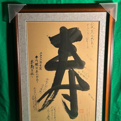 Sale Photo Thumbnail #50: Framed calligraphy artwork "Longevity", presumed to be Asian script, on brown textured paper. Surrounding annotations in delicate script are present in black ink. Secured within a wooden frame with a metallic inner trim and corner protectors for shipping.