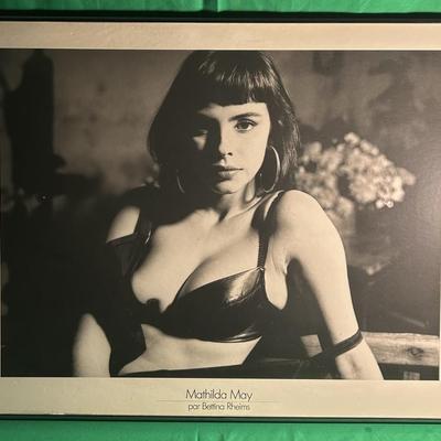 Sale Photo Thumbnail #67: Black-and-white photograph print featuring actress Kathleen Kinmont in a posed setting. The photo shows Kinmont wearing a black top and hoop earrings, with a background featuring blurred objects. Print is framed under protective glass and appears to be mo