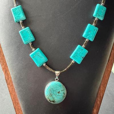 necklace made of turquoise-dyed howlite square beads and a round pendant.
