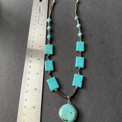 necklace made of turquoise-dyed howlite square beads and a round pendant.