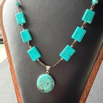 necklace made of turquoise-dyed howlite square beads and a round pendant.