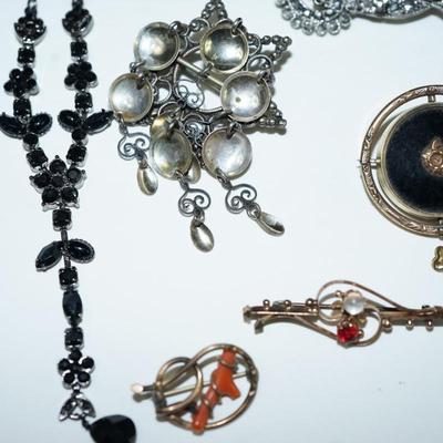 Sale Photo Thumbnail #287: various costume jewelry to include a Victorian keepsake pin, Norway solje pin and other, cameo pin, 
roman coin early pair of clip on earrings.  50's-60's porcelain brooch with hand painted courting scene, 
Clips, pins and a black rhinestone necklace with