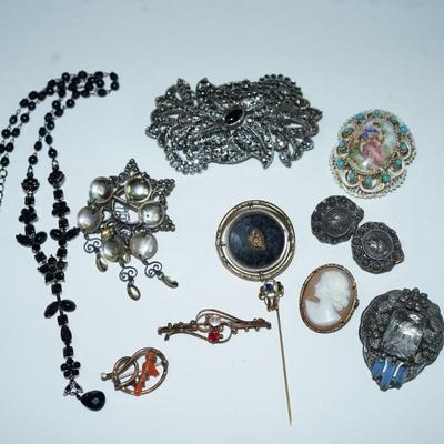 Sale Photo Thumbnail #289: various costume jewelry to include a Victorian keepsake pin, Norway solje pin and other, cameo pin, 
roman coin early pair of clip on earrings.  50's-60's porcelain brooch with hand painted courting scene, 
Clips, pins and a black rhinestone necklace with