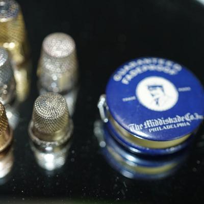 Sale Photo Thumbnail #296: grouping of five thimbles two are stamped sterling, one maybe silverplate, one is rose gold plate and the other is brass, 
vintage tape measure of cloth tape and works good,