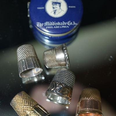 Sale Photo Thumbnail #298: grouping of five thimbles two are stamped sterling, one maybe silverplate, one is rose gold plate and the other is brass, 
vintage tape measure of cloth tape and works good,