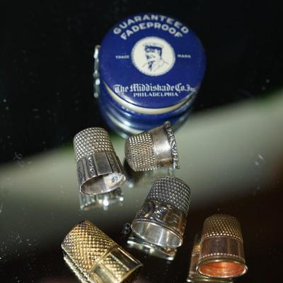 Sale Photo Thumbnail #297: grouping of five thimbles two are stamped sterling, one maybe silverplate, one is rose gold plate and the other is brass, 
vintage tape measure of cloth tape and works good,