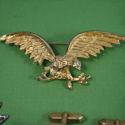 Sale Photo Thumbnail #308: two class rings, onyx and sterling?
white metal and brass watch fobs
eagle pin signed
two avaiator pins -sterling
merchant marine pin - sterling'
brass cuff link of roman coin repro 
rose gold plate golf or card pencil
Alva sun burst pendant 
other...