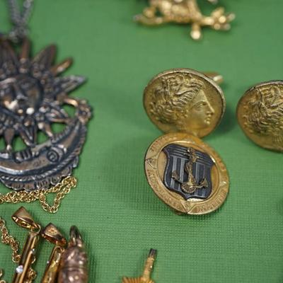 Sale Photo Thumbnail #307: two class rings, onyx and sterling?
white metal and brass watch fobs
eagle pin signed
two avaiator pins -sterling
merchant marine pin - sterling'
brass cuff link of roman coin repro 
rose gold plate golf or card pencil
Alva sun burst pendant 
other...