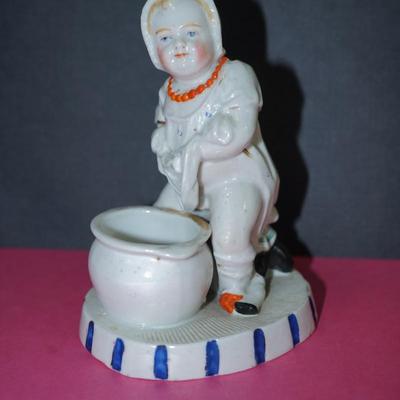 Sale Photo Thumbnail #362: Circa 1910 glazed porcelain match keep, the base of the figurine is a stike for the match, 
Little novelty of a baby about to sit on the commode. Its doll behind him. 
Height 5" 
the base measiures 4" by 3 1/4"
Good condition, slight wear to the base. and