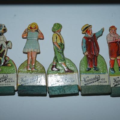 Sale Photo Thumbnail #402: grouping of 11 Kennedy Dairy carboard cut outs of children and advertising of Kennedy Dairy of Madison, WI 
I would guess these are from the 30's . In good condition and good color except for one the face is missing. 
Otherwise these are a perfect project