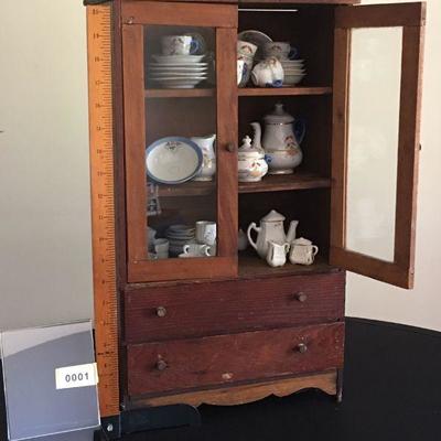 Charming miniature cabinet complete with miniature dishes.