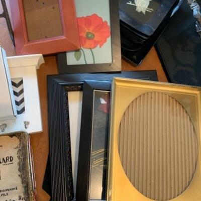 Lot 46. Assorted frames, lacquer serving trays, cheese plates, large coasters, luncheon placemats, pair of mid-century otter figures,...