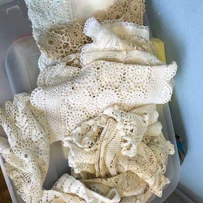 Plastic bin filled with lacy curtains, table runners, table cloths (149)