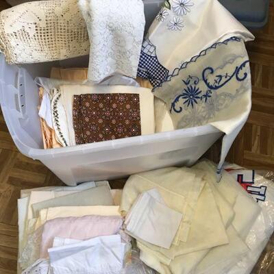 Plastic bin filled with lacy curtains, table runners, table cloths (149)