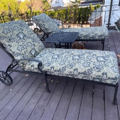 Two cast aluminum chaises with cushions and side table 