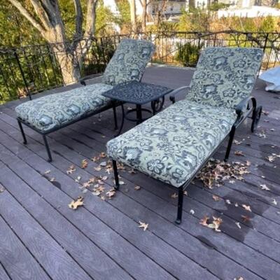 Two cast aluminum chaises with cushions and side table 