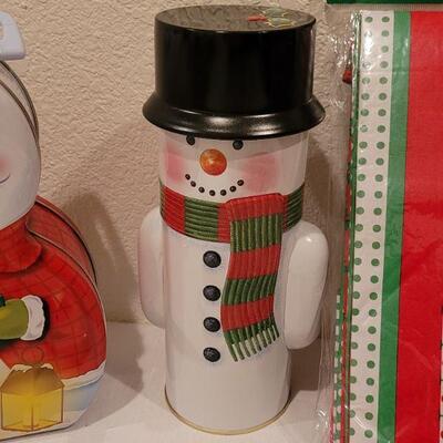 Lot 138: NEW Christmas Cheer Kitchen Lot- 6 Packages of Disposable Napkins,  Disposable Plates, Tablecloth & Snowman Tins