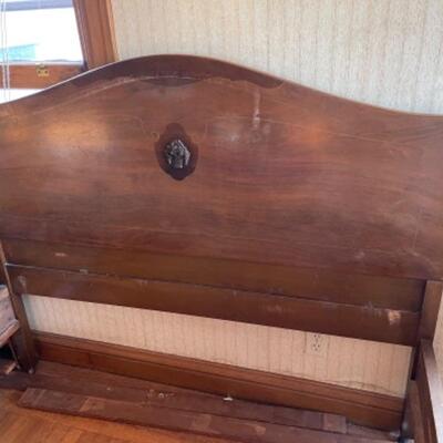 Lot 92. 1940s double bedframe (77.5â€L x 54.5â€W), wood with curved footboard on wooden casters--$35