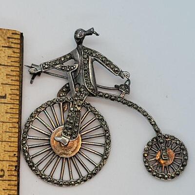 Lot JMO4: Large Silver and Marcasite Brooch of a person riding a penny farthing high bike. Articulated wheels. 