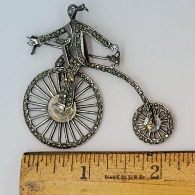 Lot JMO4: Large Silver and Marcasite Brooch of a person riding a penny farthing high bike. Articulated wheels. 