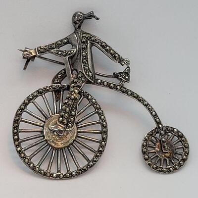Lot JMO4: Large Silver and Marcasite Brooch of a person riding a penny farthing high bike. Articulated wheels. 