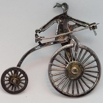 Lot JMO4: Large Silver and Marcasite Brooch of a person riding a penny farthing high bike. Articulated wheels. 