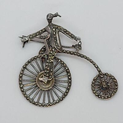 Lot JMO4: Large Silver and Marcasite Brooch of a person riding a penny farthing high bike. Articulated wheels. 