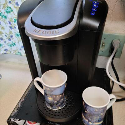 Keurig coffee maker/ pod holder rack/ and 2 Thomas Kinkade mugs. 