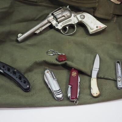 Lot 103 Military Duffel bag and 6 pocket knives, 1 vintage Western cap gun