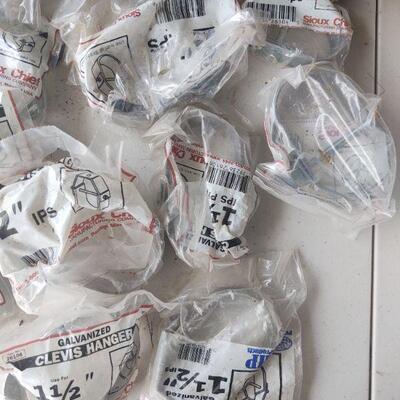 lot 198 - assorted plumbing parts in original packaging - galvanized clevis hangers, gas log part, etc.