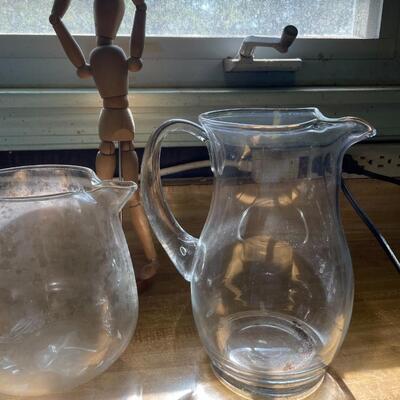 lot 87- (3) glass pitchers, (2) watering cans, wooden decor piece
