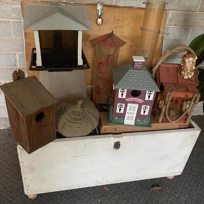 Array of birdhouses and white wooden trunk on casters.