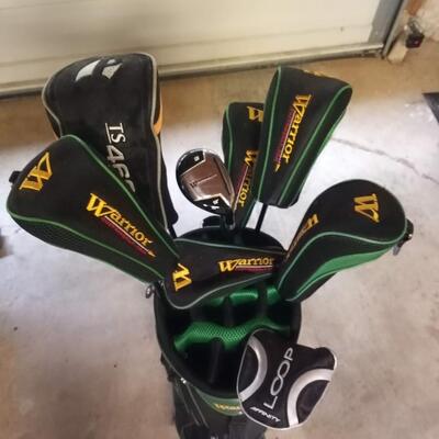 Black and green Warrior golf bag with 7 clubs and specialty tool
