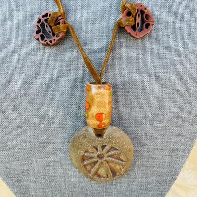 AA   GROOVY HIPPY PENDANT OF CLAY W/CERAMIC BEADS & WALNUT SLICES STRUNG ON LEATHER.