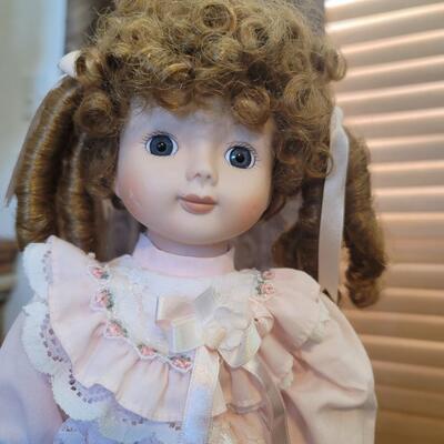 Curly haired porcelain doll on stand