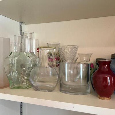 2 shelves full of glass and other materials vases