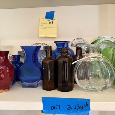 2 shelves full of glass and other materials vases