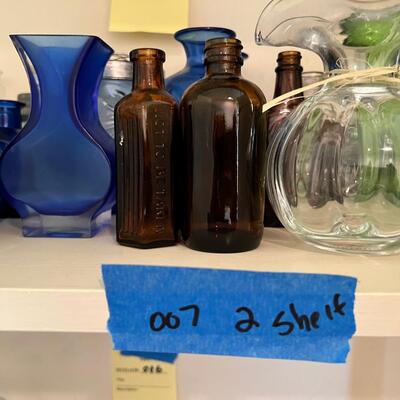 2 shelves full of glass and other materials vases