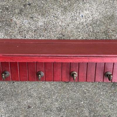 Red shelf with brass hooks