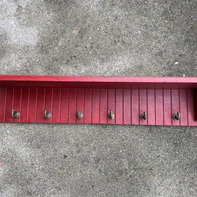 Red shelf with brass hooks