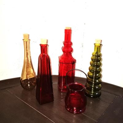 FOUR COLORED GLASS BOTTLES AND GLASS CANDLE HOLDER
