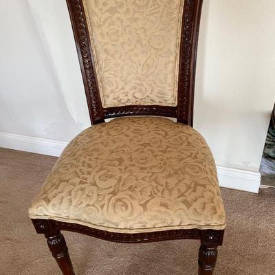 Beige upholstered ornately carved wooden chair